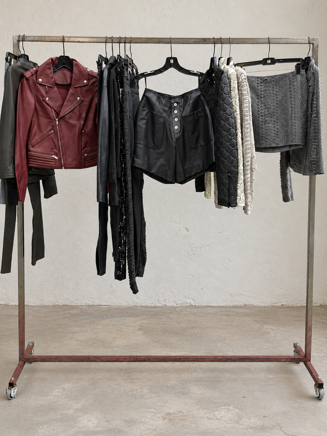 Burgundy, black and charcoal studded leather jackets, pants and shorts on a garment rack